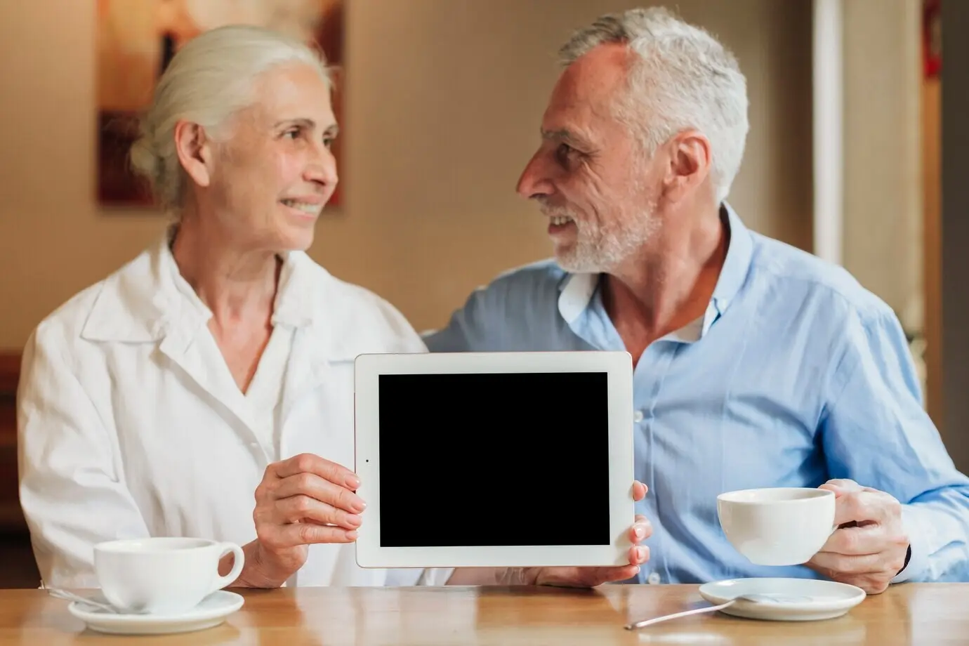 Plano medio de una pareja sosteniendo una maqueta de una tableta.